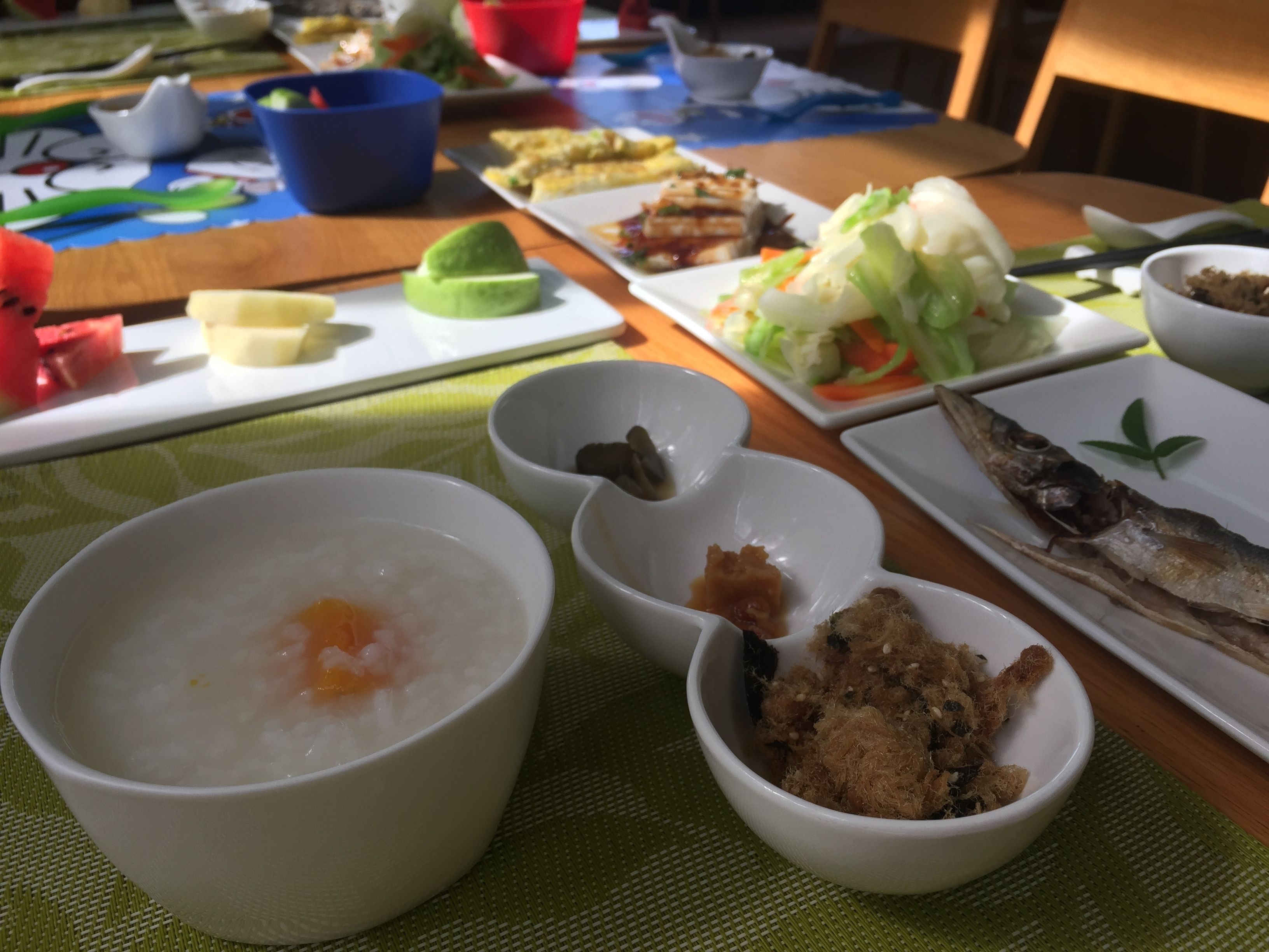 Una mesa con varios platos, incluyendo un tazón de arroz, un pescado y una ensalada.