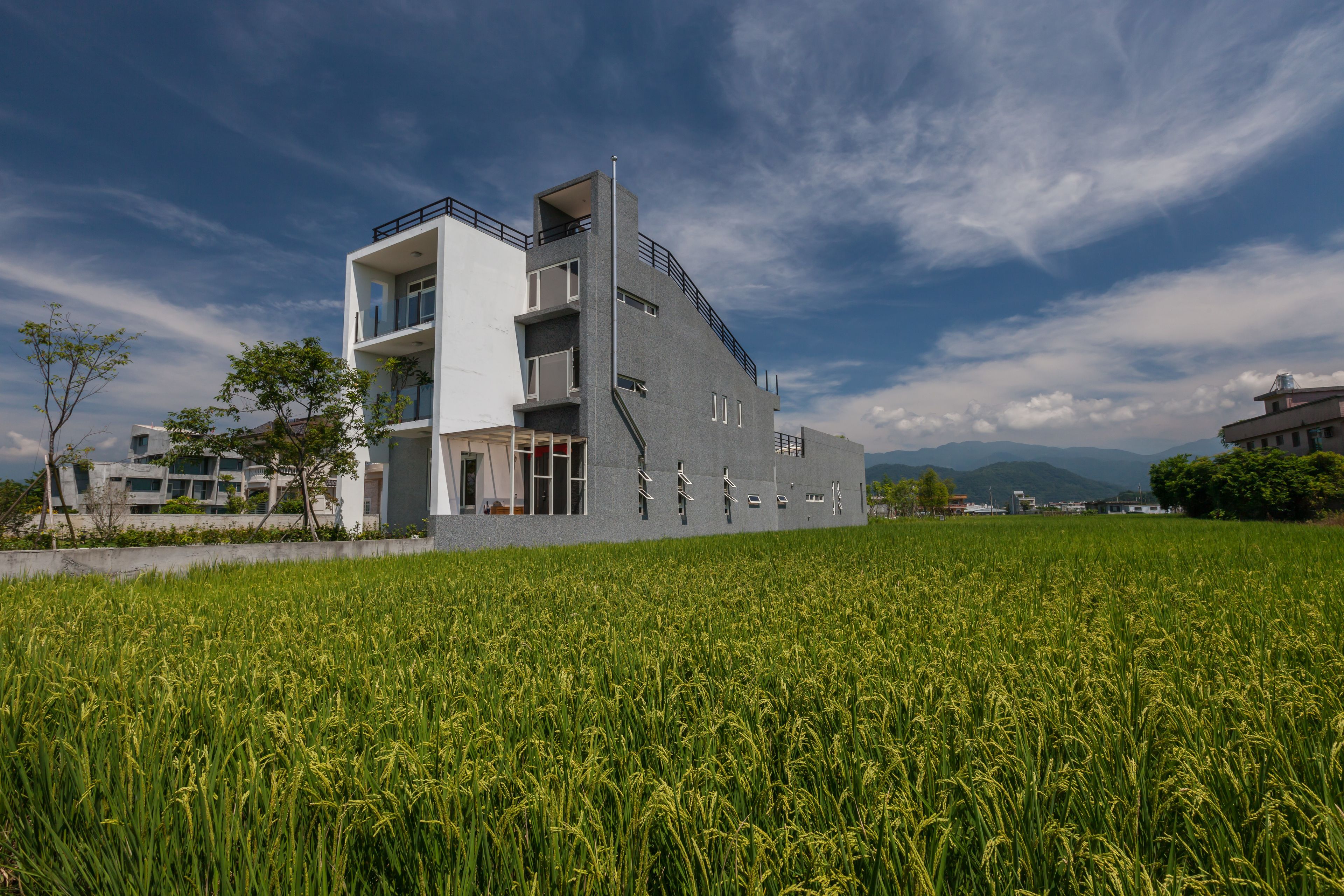 A modern building with a unique architectural design, situated in a lush green field.
