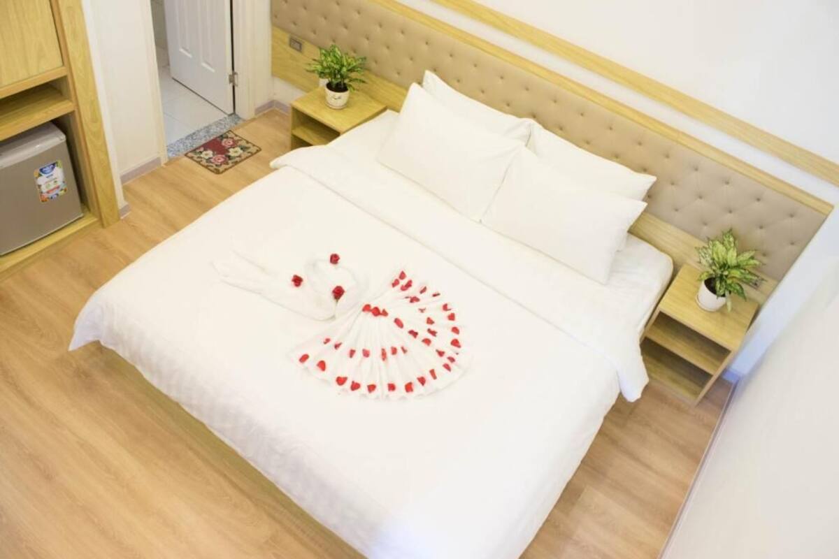 A neatly made bed with white linens and a decorative red and white design on the bedspread.