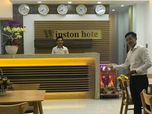 A reception desk with a sign reading "Winston Hotel" and four clocks above it. - Winston Hotel (Ho Chi Minh City)