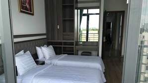 Habitación de hotel con dos camas, un ventanal grande y vistas al exterior.