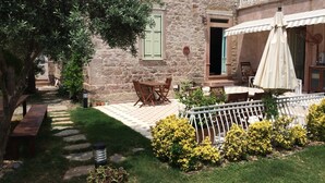 A stone building with a courtyard, outdoor seating, and a potted plant. - Cunda Has Konak Otel (Ayvalik)