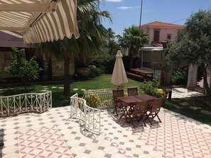 A patio with a patterned tile floor, outdoor furniture, and a covered seating area.