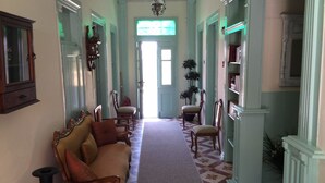 A hallway with a sofa, chairs, a carpet, and a bookshelf. - Cunda Has Konak Otel (Ayvalik)