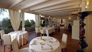 A restaurant with round tables set for dining, a view of the outdoors, and a decorative sculpture.