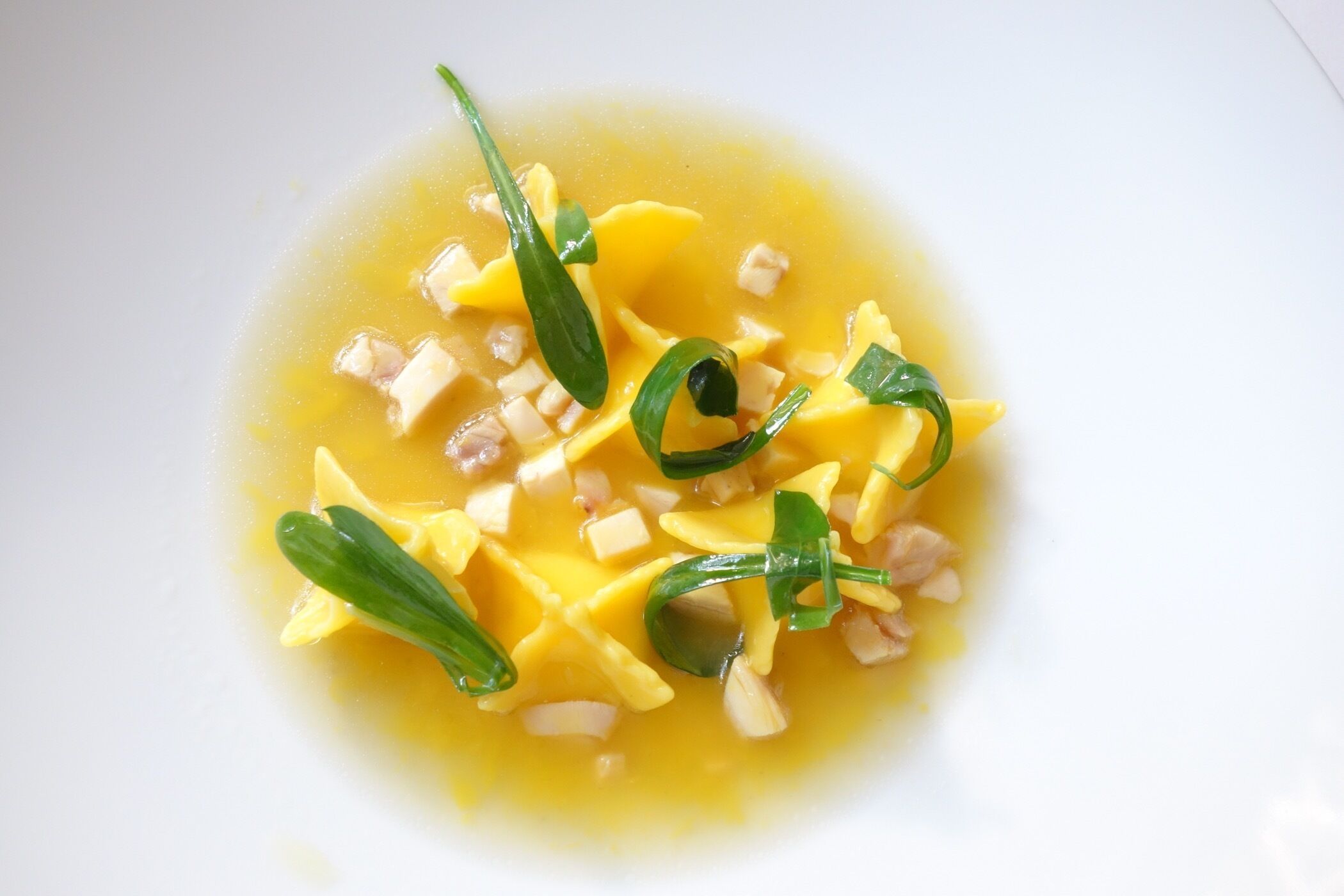 A bowl of soup with noodles and green onions.