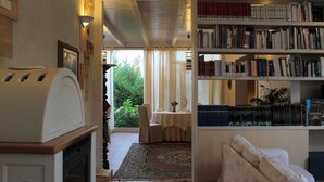 A cozy living room with a fireplace, a bookshelf, and a dining area with a table and chairs.