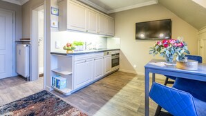 Una cocina moderna con armarios blancos, horno empotrado y comedor con una silla y una mesa azules.