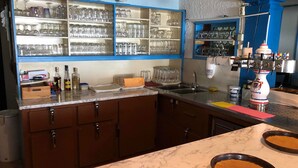 A kitchen with a marble countertop, a sink, and a shelf with glassware. - Hotel Kreta (Ueberlingen)