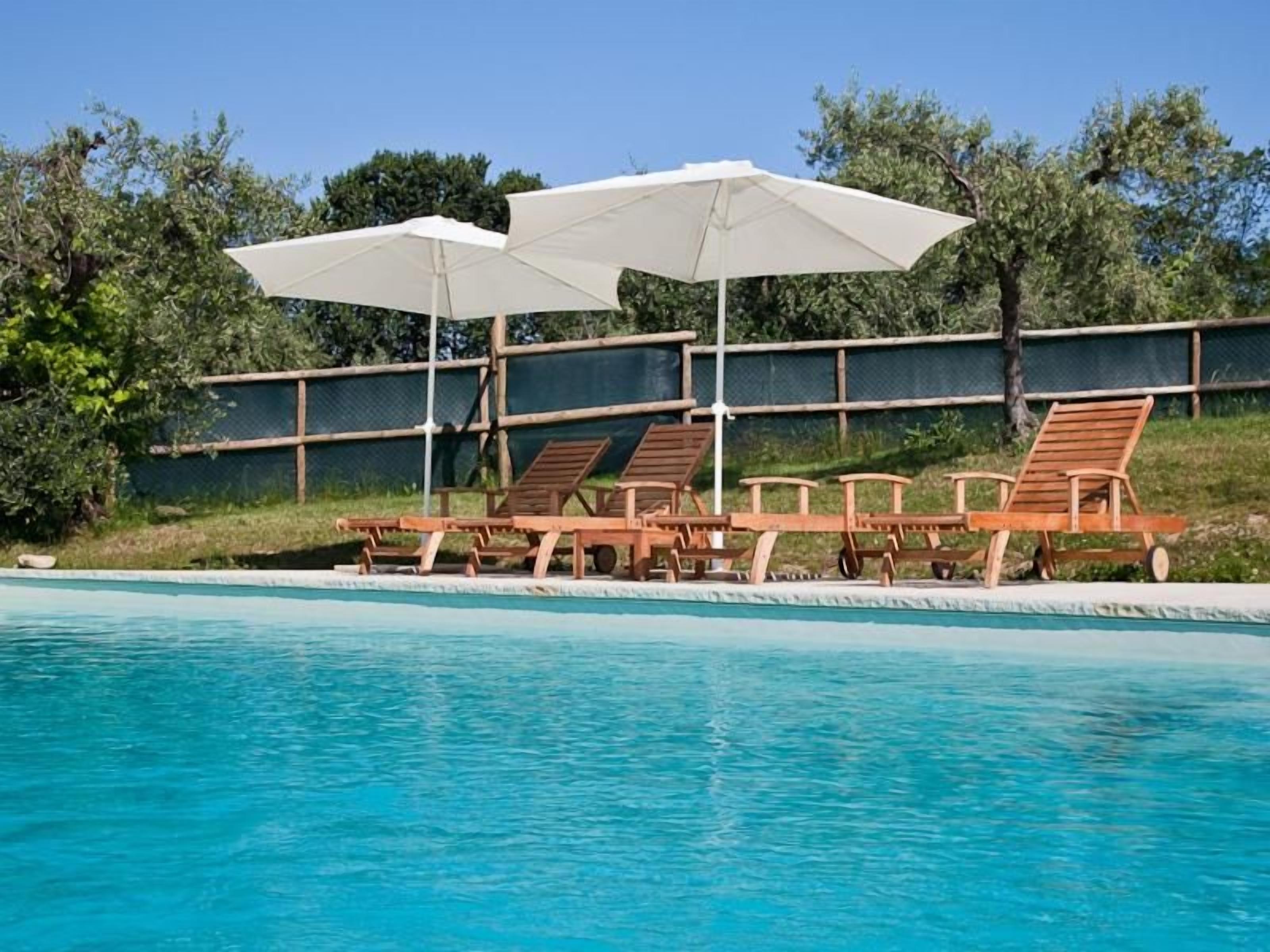 Una piscina con sillas de descanso y sombrillas.