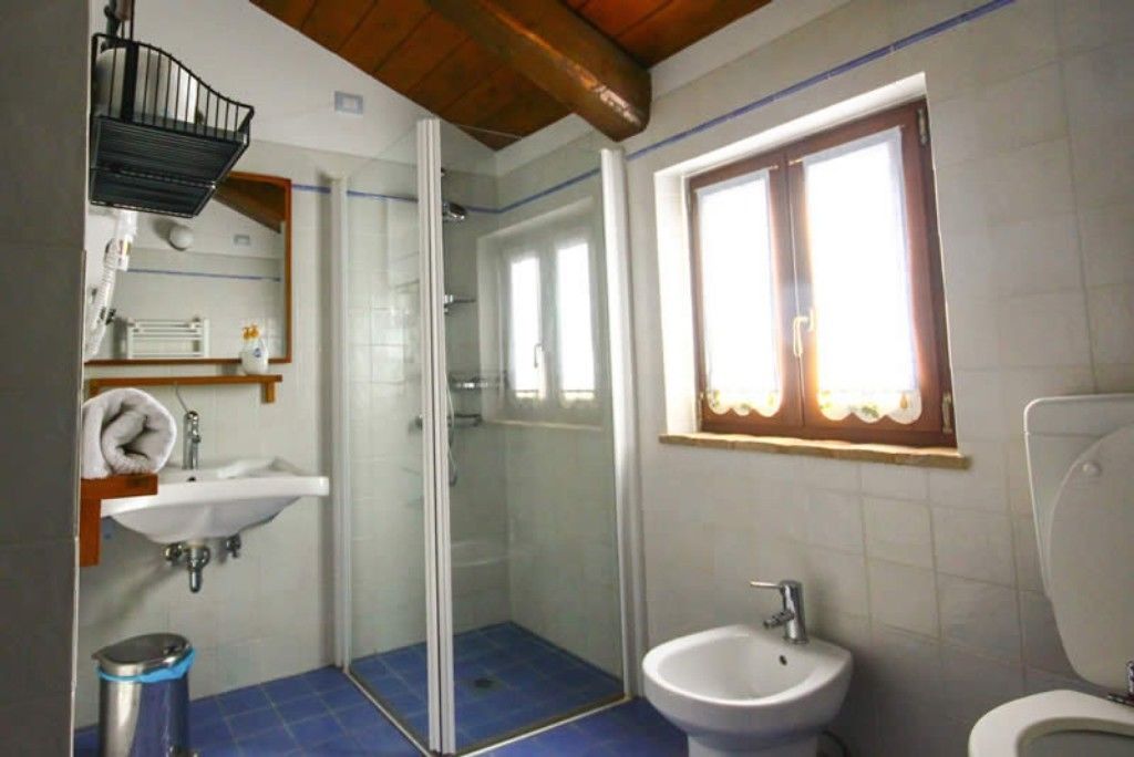 Un baño con ducha de vidrio, lavamanos, bidé e inodoro.