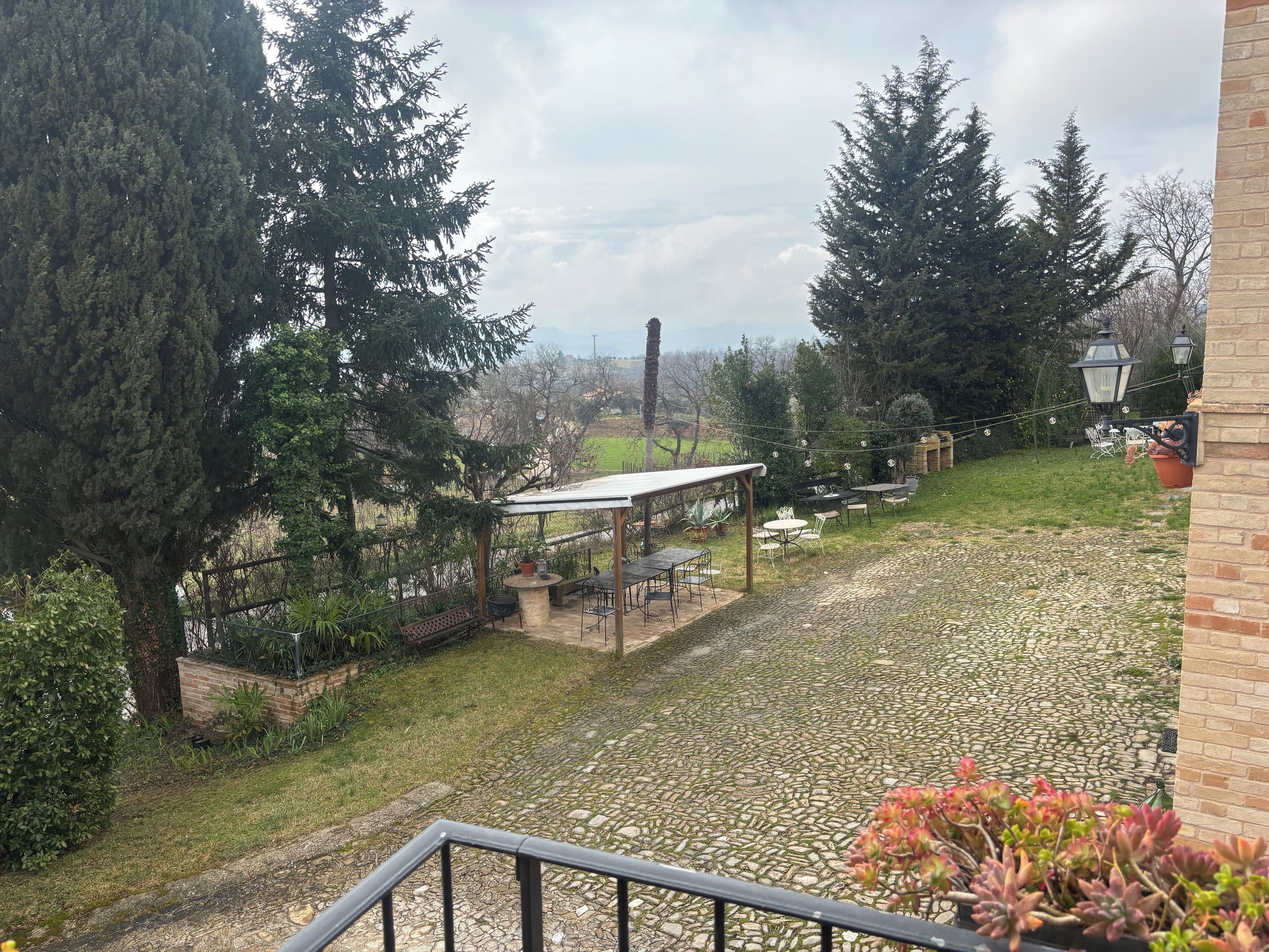 Un patio con mobiliario exterior, una pérgola y vistas a un paisaje lejano.