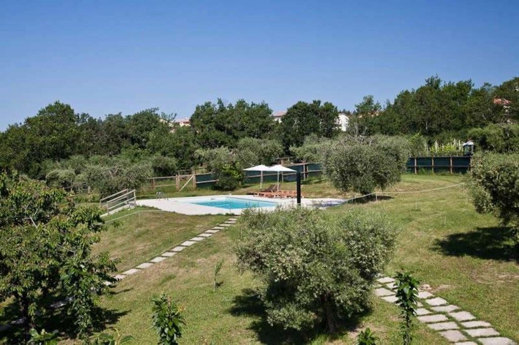 Un giardino sul retro con piscina, un'area salotto coperta e un vialetto in pietra.