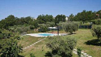 Un patio trasero con piscina, zona de estar cubierta y un sendero de piedra.