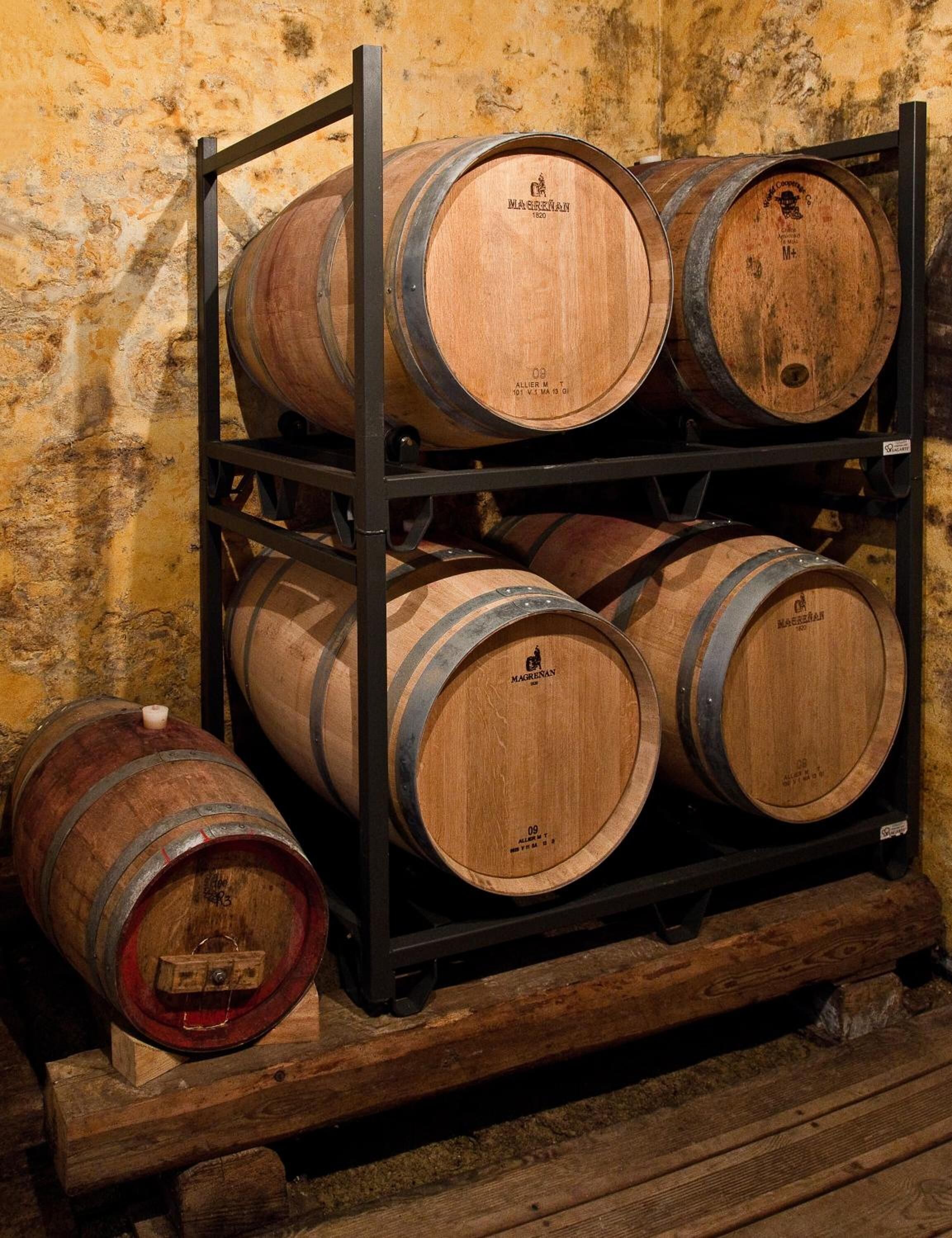 A rack of wooden wine barrels against a textured wall.
