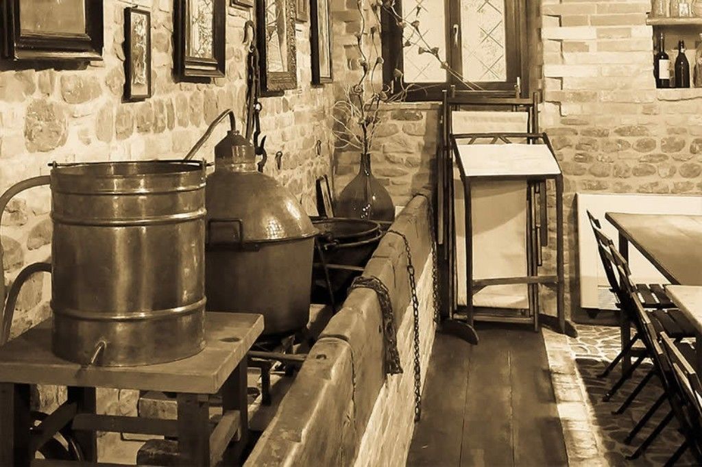 Une cuisine rustique aux murs de pierre, avec des ustensiles de cuisine en métal et une table en bois.
