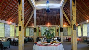 Un comedor espacioso con techos altos y ventanas amplias, con una mesa central dispuesta para una comida.
