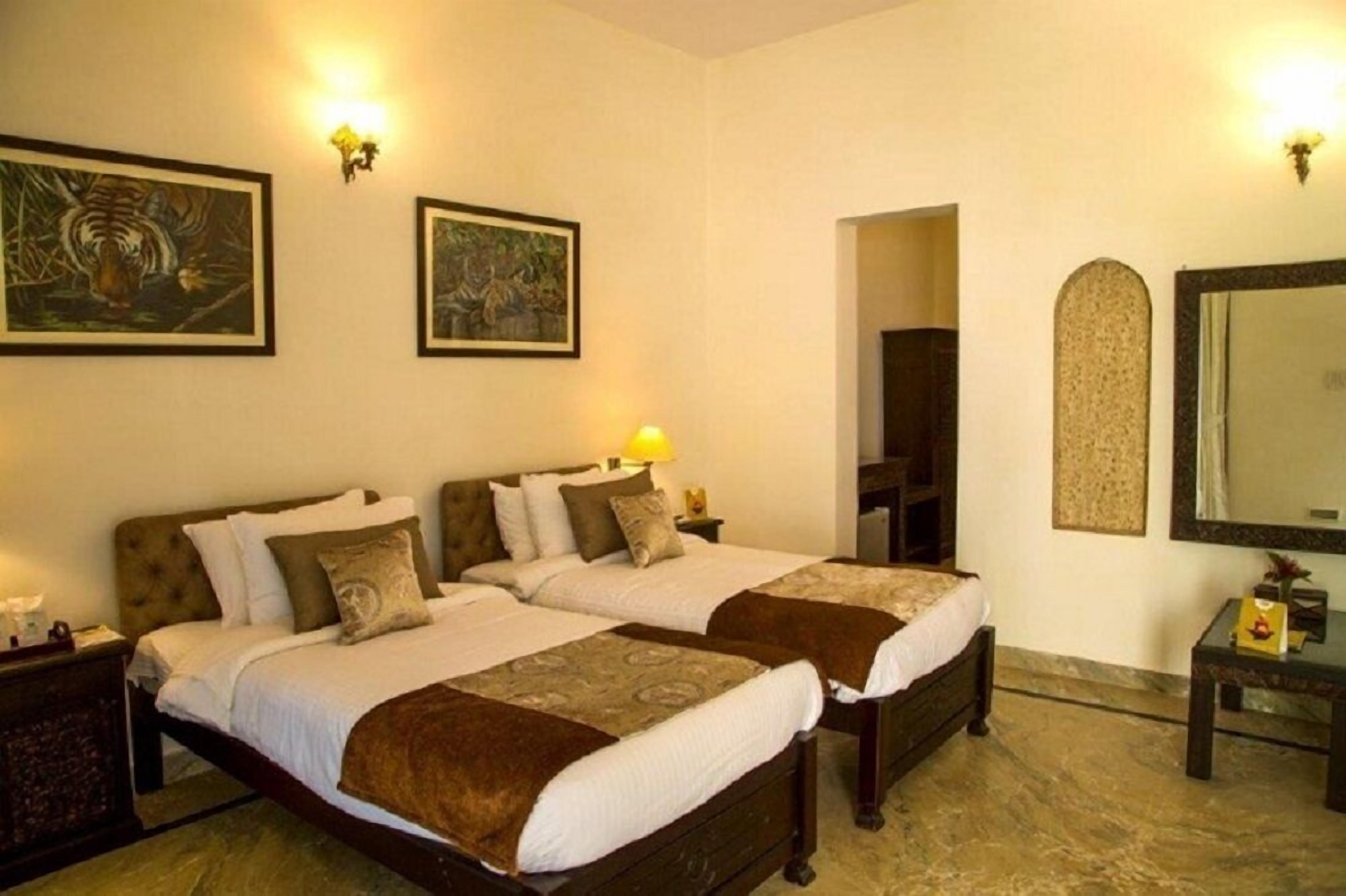 A hotel room with two beds, a large mirror, and artwork on the walls.