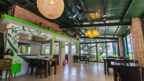 A restaurant with brick walls, large windows, and a green accent wall. Tables and chairs are arranged for dining. - Locasu B&B (Datong)