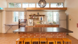 A kitchen with a brick island, wooden stools, a coffee maker, and a refrigerator. - Locasu B&B (Datong)