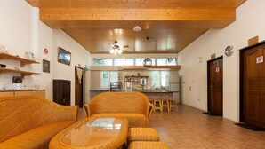 A spacious living area with wicker furniture, a ceiling fan, and a kitchen in the background. - Locasu B&B (Datong)