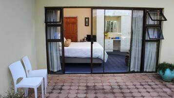 A hotel room with a bed, a desk, and a bathroom visible through a sliding door.
