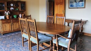 A dining area with a wooden table and chairs, a cabinet with dishes, and a painting on the wall. - Unique Bed and breakfast (Harare)