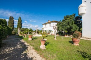 A villa with a garden path leading to a white building, surrounded by potted plants and trees. - Villa Dell'Annunziata (Rieti)