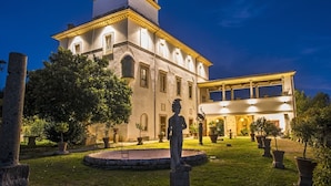 Un edificio histórico con un patio central, una estatua y un jardín bien cuidado.