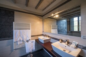 Um banheiro moderno com duas pias, um espelho grande e um porta-toalhas.