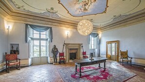 Una sala majestuosa con chimenea, candelabro y un gran tapiz.