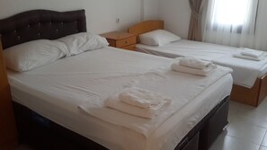 Ein Hotelzimmer mit zwei Betten, jeweils mit weißer Bettwäsche und Kissen, jeweils ein hölzernes Kopfteil und ein Nachttisch mit Lampe.