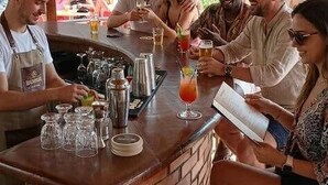 A bar area with a brick counter, glasses, and a person pouring a drink. - Hotel Delta Altinkum (Didim)