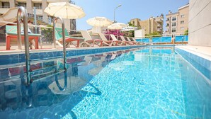 A swimming pool with clear blue water, sun loungers, and umbrellas. - Hotel Delta Altinkum (Didim)