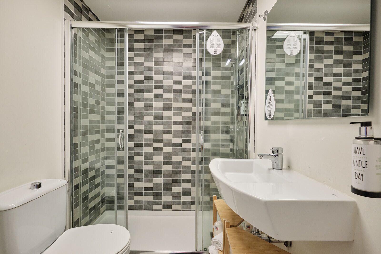 Une salle de bain moderne avec une douche à parois de verre, un lavabo blanc et des toilettes.