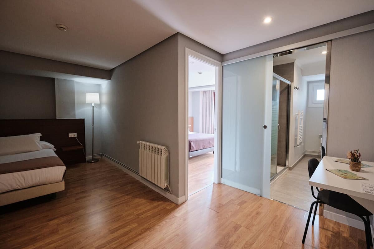 A bedroom with a bed, bedside table, lamp, and a radiator.