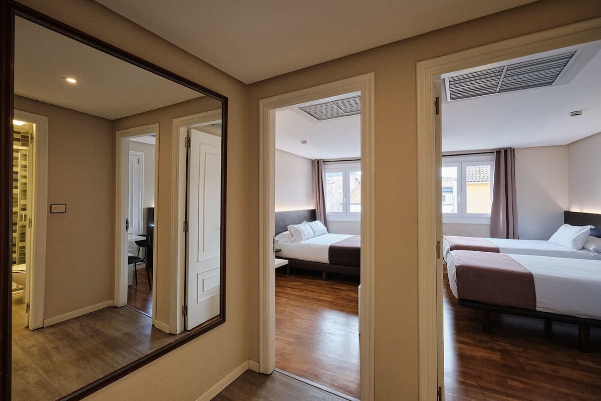 A hotel room with a large mirror, two beds, a desk, and a chair.
