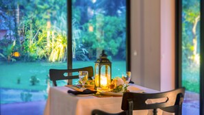 A table set with a candle, glasses, and a lantern, overlooking a lush garden. - EKHO Weligama (Weligama)
