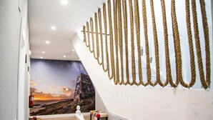 Un escalier avec une rampe blanche et un mur décoré d’un motif rappelant une corde.