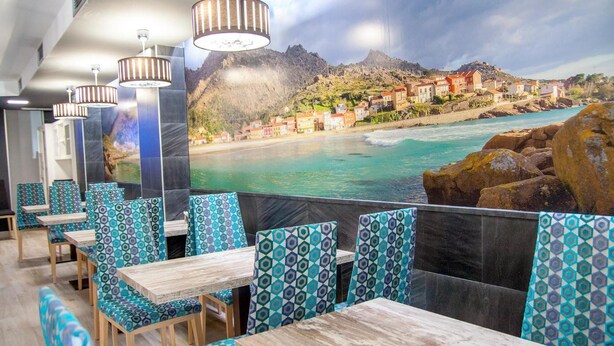 Un restaurant offrant une vue sur la côte, avec des sièges aux motifs originaux et un éclairage moderne à suspension.