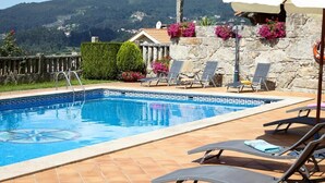 A swimming pool with a decorative edge, surrounded by lounge chairs and potted plants. - Hotel Liñares (Poio)