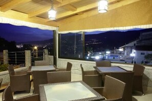 An outdoor seating area with wicker furniture and a view of a cityscape at night.