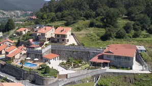 A residential area with houses, a swimming pool, and a stone wall. - Hotel Liñares (Poio)