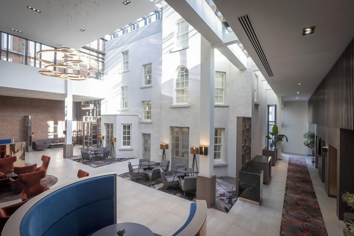 Een ruime hotellobby met hoge plafonds, een centraal gelegen zithoek en uitzicht op de buitenkant van het gebouw.