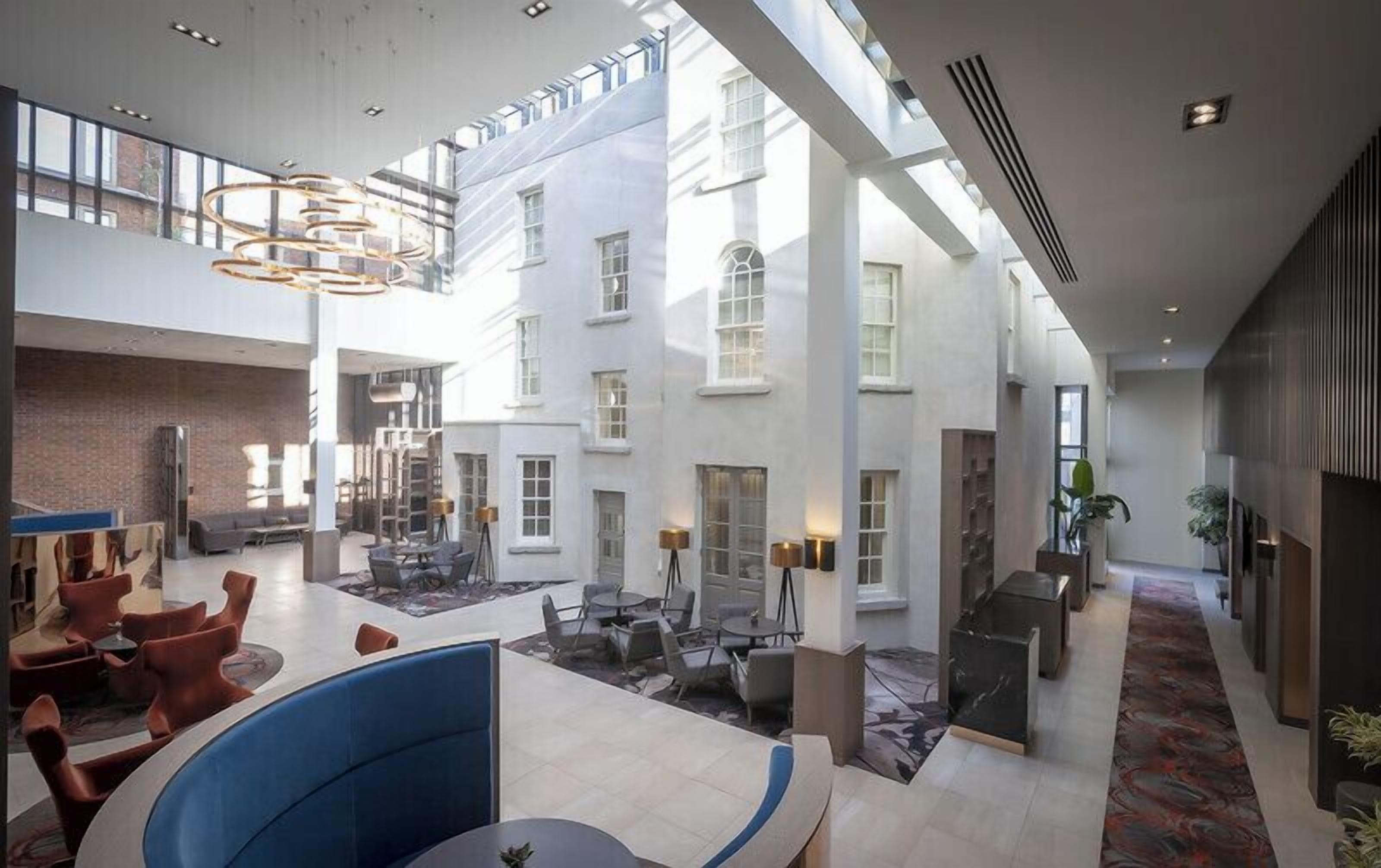 A spacious hotel lobby with high ceilings, a central seating area, and a view of the building's exterior.