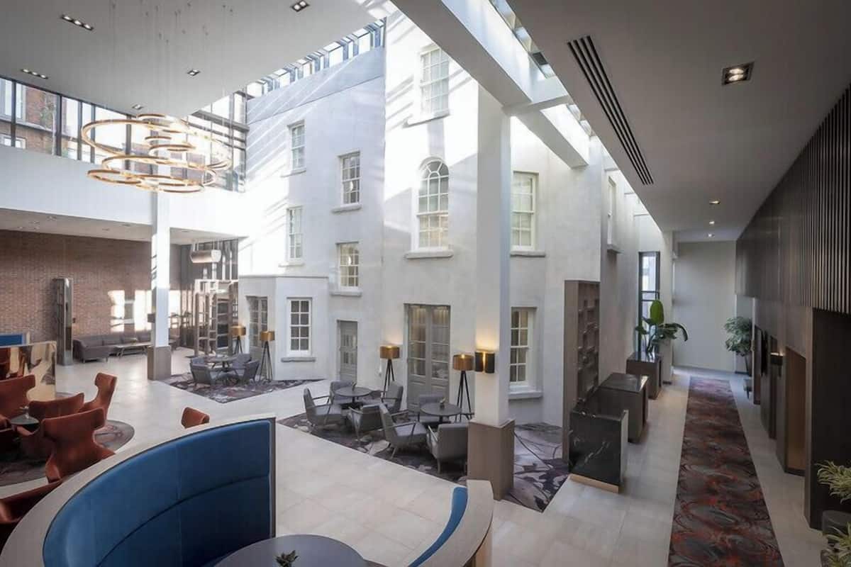 Een ruime hotellobby met hoge plafonds, een centraal gelegen zithoek en uitzicht op de buitenkant van het gebouw.