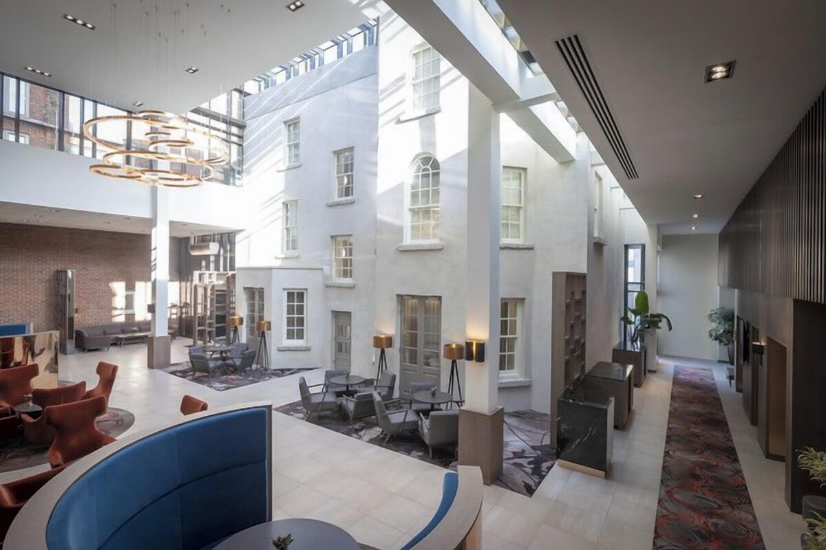 A spacious hotel lobby with high ceilings, a central seating area, and a view of the building's exterior.