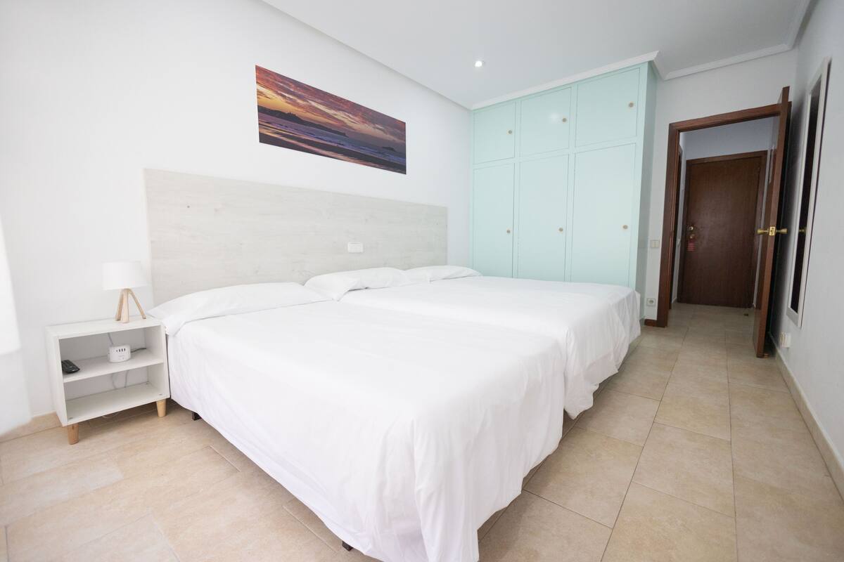 Une chambre avec deux lits, une table de chevet, une armoire et un tableau au mur.