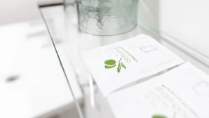 A glass display case with a textured glass bottle and a card with text and a leaf design.