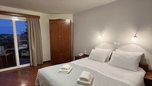 A hotel room with a large bed, two bedside tables, a wardrobe, and a sliding glass door leading to an outdoor area. - Iolkos Hotel Apartments (Chania)